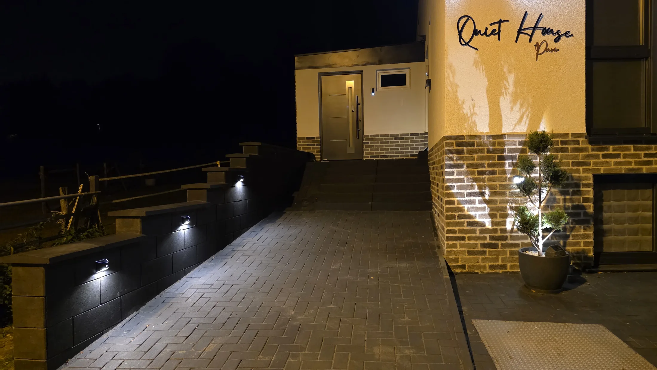 Beleuchteter Eingang des Quiet House Pure am Abend, Leverkusen-Steinbüchel